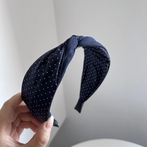 Detail view of navy blue polka dot fabric headband with a vintage twisted knot design