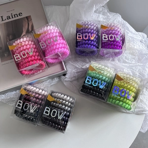 Macro shot of colorful gradient spiral hair ties in transparent square gift boxes