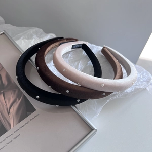 Detail of three velvet headbands with white pearls in black, brown and cream colors