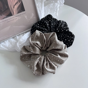 Gros plan de grands chouchous en satin avec strass argentés en noir et gris champagne