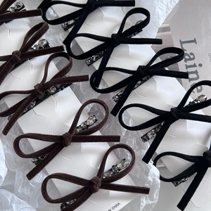 Dettaglio di fermagli per capelli a fiocco in velluto con strass in nero e marrone su carta