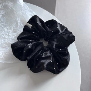 Detail of large black velvet hair scrunchie with sparkling rhinestones on white display
