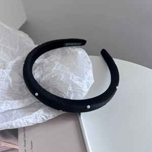 Detail shot of a handmade black velvet headband with elegant pearls and label