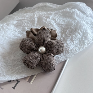 Detail of tweed flower hair tie with white faux pearl and brown satin ruffle