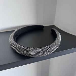 Detailed view of wide padded headband with sparkling grey rhinestones on a display stand