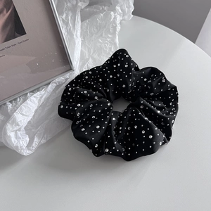 Gros plan d'un chouchou en satin noir avec strass brillants sur fond de décor artistique