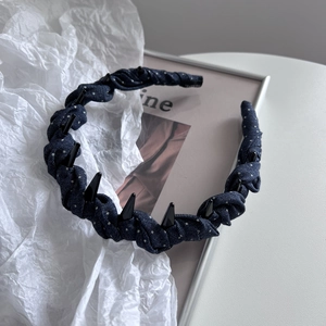Detailed close-up of dark blue polka dot headband with black stud rivets and woven fabric texture