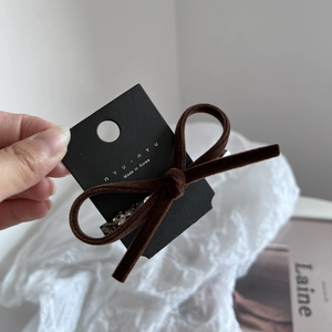 Dettaglio del fermaglio per capelli a fiocco in velluto caffè con strass su carta