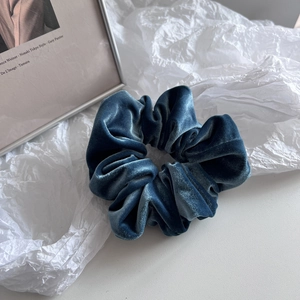 Macro shot of dark blue velvet scrunchie showing plush texture and elastic pleated design