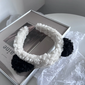 Close-up of fluffy panda faux fur headband with black ears on a minimalist desk