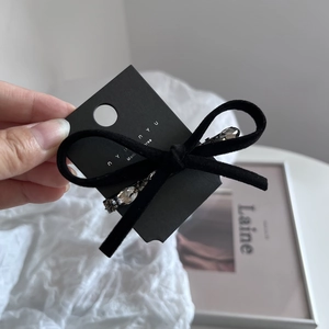 Dettaglio di un fermaglio per capelli in velluto nero con strass lucenti su carta