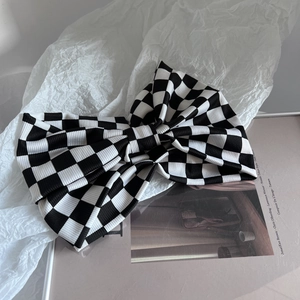 Detailansicht eines karierten Stirnbands mit großer Schleife auf minimalistischem Papier
