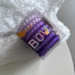 Close-up of purple spiral hair ties in a transparent square gift box with laser logo