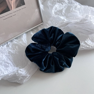 Macro shot of dark blue velvet scrunchie showing soft texture and pleated details
