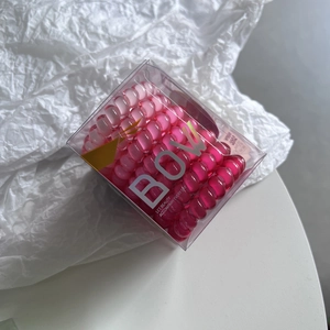 Detailed view of pink gradient spiral hair ties inside a clear plastic storage box