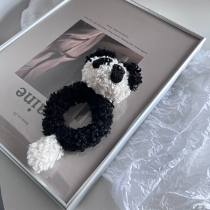 Detailed view of a plush panda hair scrunchie with soft black and white faux fur texture