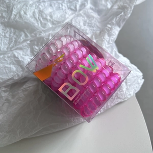 Macro detail of gradient pink spiral hair ties in transparent box with BOW branding