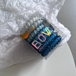 Detail of high-elastic gradient blue spiral hair ties set in a clear plastic square box