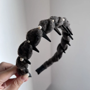 Close-up of grey tweed headband with hand-sewn pearls and black spiked accents