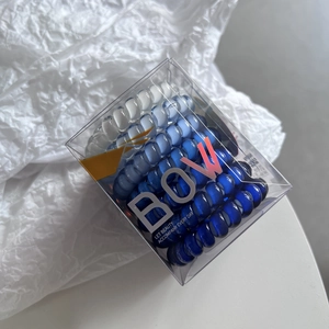 Detail of gradient blue spiral hair ties organized in a clear transparent square box