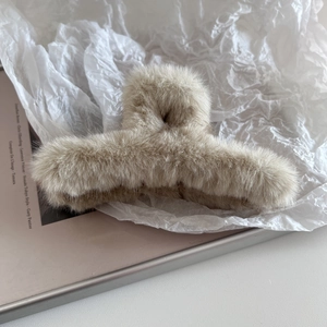 Gros plan sur la texture en fausse fourrure et le design de la pince à cheveux beige