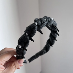 Close-up of hand-sewn pearls and black triangular accents on a dark grey wool headband