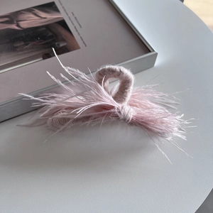 Close-up of light pink ostrich feather hair claw clip with soft plush fabric texture