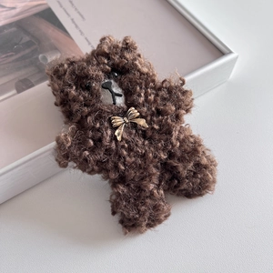 Nahaufnahme der braunen Plüschbär-Haarspange mit goldener Schleife und NICE-Aufdruck