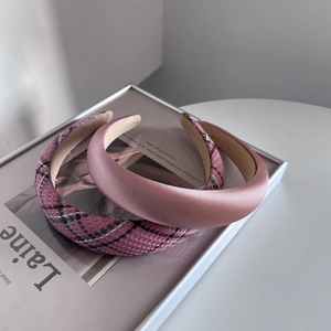 Serre-têtes en satin rose et tweed à carreaux posés sur un magazine de mode chic