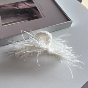 Detail of white ostrich feather hair claw clip with soft knitted texture and fluffy design