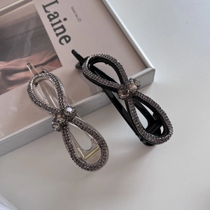 Gros plan sur des barrettes à nœuds en strass brillants sur un fond blanc épuré
