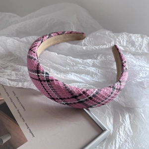 Gros plan du serre-tête à carreaux roses montrant la texture du tissu et le bord large