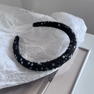 Detail of black sequined headband with silver sparkles on textured velvet fabric