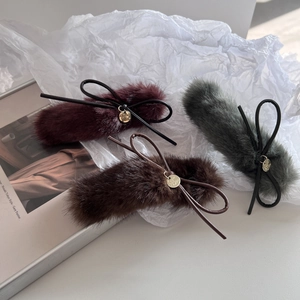 Détail de pinces à cheveux en peluche avec nœuds en cuir et pendentifs dorés élégants