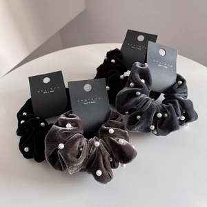 Elegant velvet hair scrunchies with white pearls in four colors on a white table
