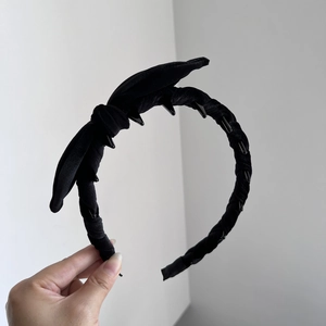 Detail of black velvet headband showing non-slip inner teeth and bow texture