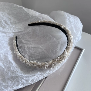 Detailed macro view of beige and gold tweed fabric texture with shiny sequins on headband