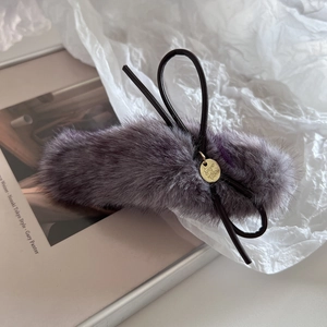 Détail de la pince à cheveux en peluche grise avec nœud noir et pendentif doré
