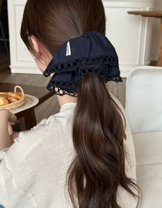 Detailed view of black fabric scrunchie with lace trim and handmade tag on hair