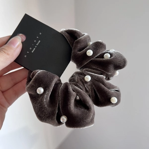 Detail of dark coffee velvet scrunchie with white pearl accents on brand display card