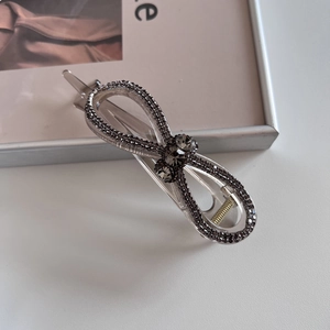 Détail de la pince à cheveux transparente en forme de nœud avec strass gris foncé poli