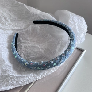 Detail of light blue denim headband featuring hand-sewn iridescent sequins and non-slip lining