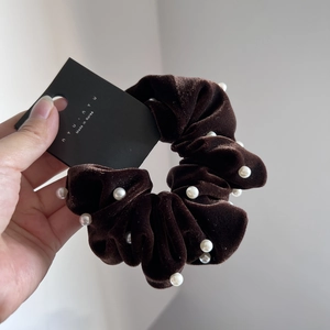 Detailed close-up of a brown velvet scrunchie featuring white pearl embellishments