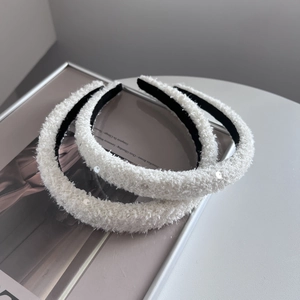 Detail of white plush headband with silver sequins and black non-slip velvet lining