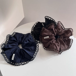 Detail of French hollow lace scrunchies in navy, black, and coffee with handmade label