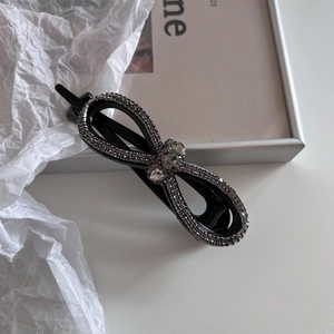 Détail d'une pince à cheveux nœud noir avec strass gris et pierres précieuses centrales