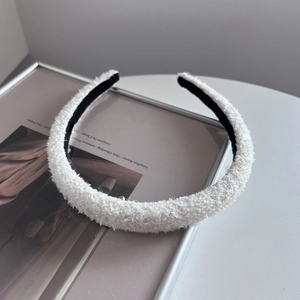 Close-up of a white plush headband with subtle sequins and black non-slip inner lining