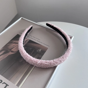 Detail of pink fuzzy headband with textured plush fabric and black inner lining