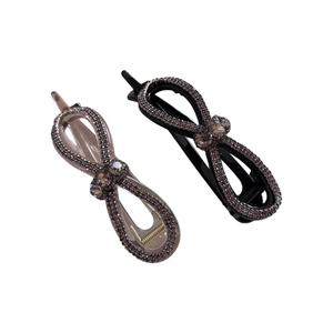 Barrettes à cheveux nœud avec strass noirs et gris et pierres scintillantes sur fond blanc