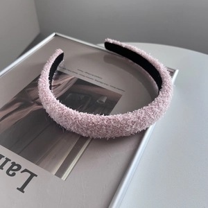 Detail of pink fleece headband with sequins on a textured bouclé fabric surface